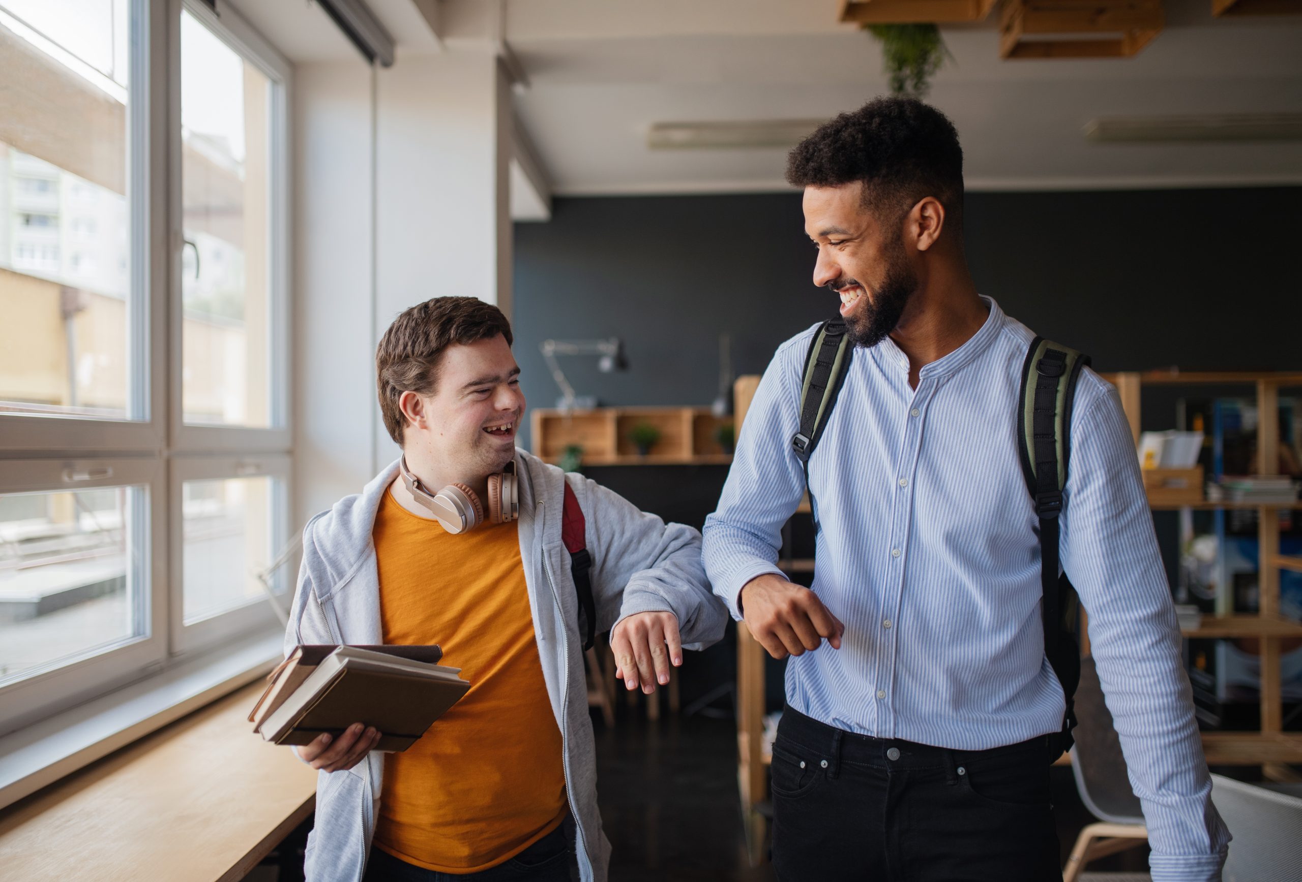 Jeune homme trisomique heureux avec son ami mentor, célébrant le succès à l'école.