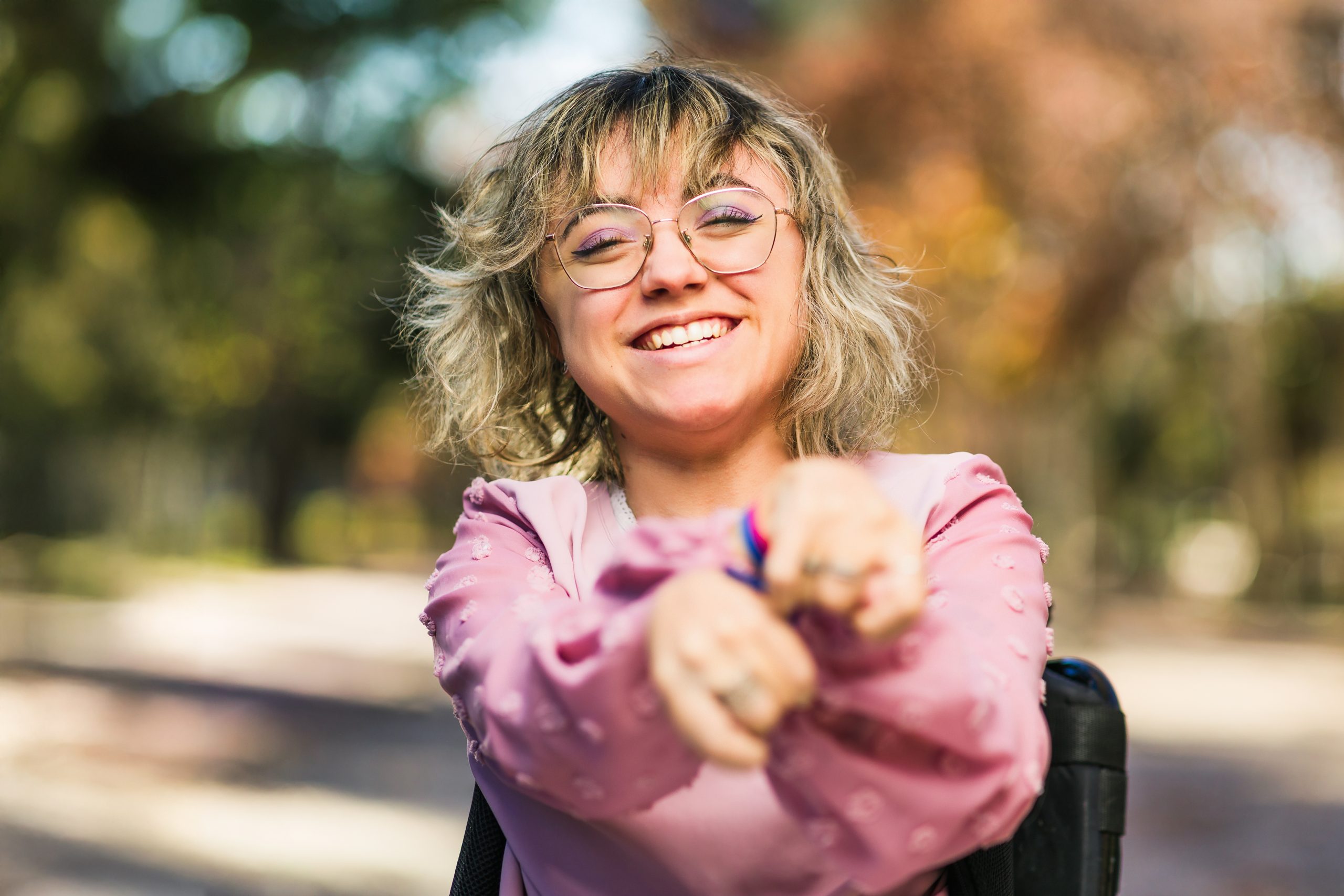 Jeune femme handicapée cérébrale avec déficience intellectuelle en fauteuil roulant, saluant et souriant. Intégration sociale